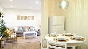 Ein modernes Wohnzimmer mit grauem Sofa, weißem Couchtisch und einem Essbereich mit rundem Tisch und Stühlen.