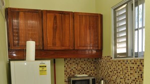A compact kitchen with wooden cabinets, a refrigerator, a microwave, a sink, and a stove.
