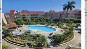 A resort with a central swimming pool, multiple buildings, and a parking area.