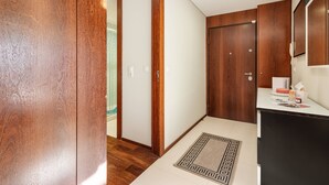 Ein Flur mit Holztüren, einer weißen Wand und einer kleinen Küchenzeile mit Arbeitsplatte und Schränken.