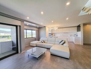A modern living room with a glass coffee table, a sofa, and a view of the city through large windows.