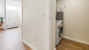 A laundry room with a washing machine and a drying rack.