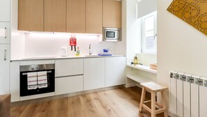 A modern kitchen with wooden cabinets, a built-in oven, a microwave, and a window with a view.