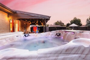 A hot tub area with a covered patio and string lights.