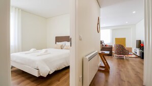 Une chambre d’hôtel moderne avec un grand lit, un petit coin salon et une vue sur le salon.