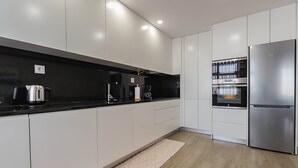 A modern kitchen with white cabinets, stainless steel appliances, and a black countertop. - Sunshine Apartment - Modern Ap Near The Beach (Viana do Castelo)