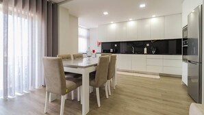 A modern kitchen with white cabinets and a black countertop. - Sunshine Apartment - Modern Ap Near The Beach (Viana do Castelo)