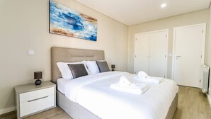 A modern bedroom with a large bed, a nightstand, a painting, and a wardrobe. - Sunshine Apartment - Modern Ap Near The Beach (Viana do Castelo)