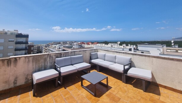 A rooftop terrace with a sofa set and a coffee table, overlooking a cityscape and the sea. - Sunshine Apartment - Modern Ap Near The Beach (Viana do Castelo)