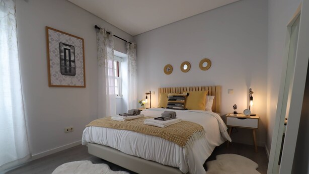 A bedroom with a bed, bedside table, and a window with curtains.