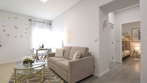 A modern living room with a beige sofa, a glass coffee table, and a patterned rug.