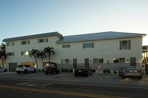 A two-story building with a flat roof and a parking lot in front.