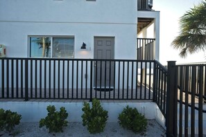 A modern building with a white facade, a black metal fence, and a door marked with the number '1'.