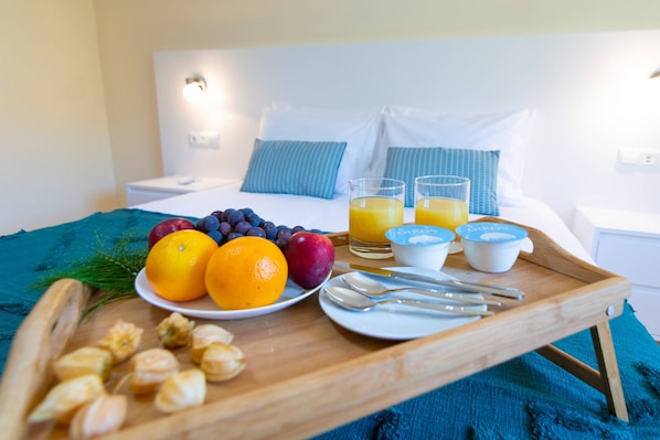 A breakfast tray with fruits, juice, and yogurt on a bed in a hotel room.