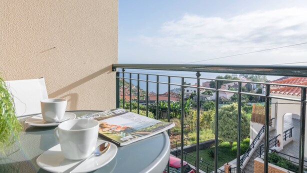A balcony with a table, two white cups, and a magazine.