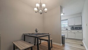 A dining area with a table and benches, a chandelier, and a kitchen in the background. - Cozy & Charming 2-bedroom, 2 bath in Central location near Cincinnati (Erlanger)