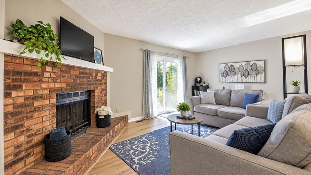 A living room with a brick fireplace, a sofa set, a coffee table, and a large window with curtains. - Cozy & Charming 2-bedroom, 2 bath in Central location near Cincinnati (Erlanger)