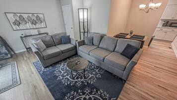 A modern living room with a grey sofa set, a coffee table, and a patterned rug.
