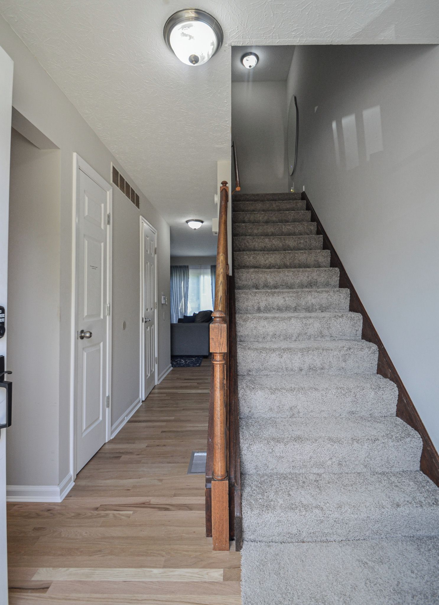 Un escalier avec des balustrades en bois et des marches recouvertes de moquette, menant à un palier situé au deuxième étage.