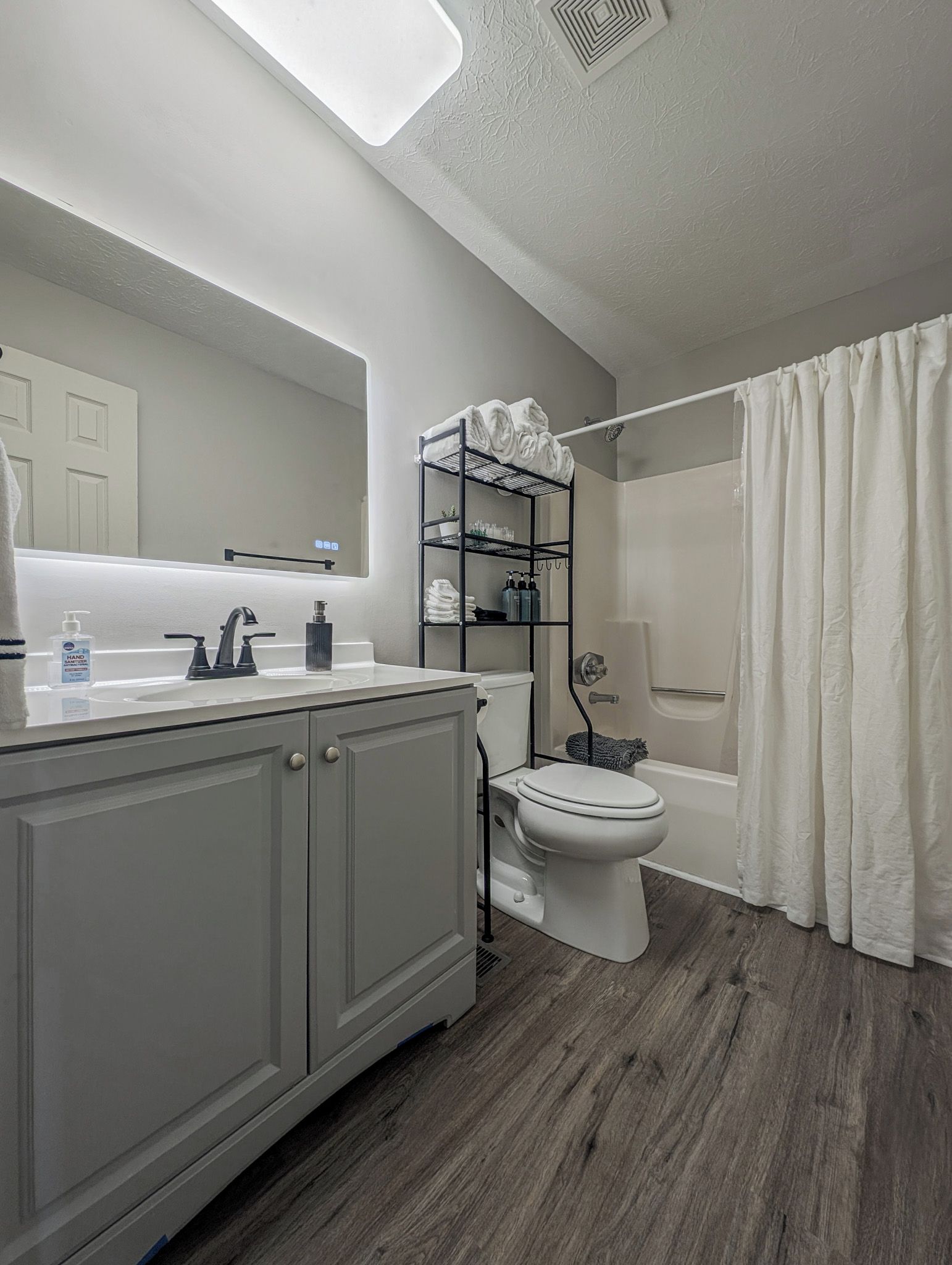 A modern bathroom with a white sink, toilet, and shower.