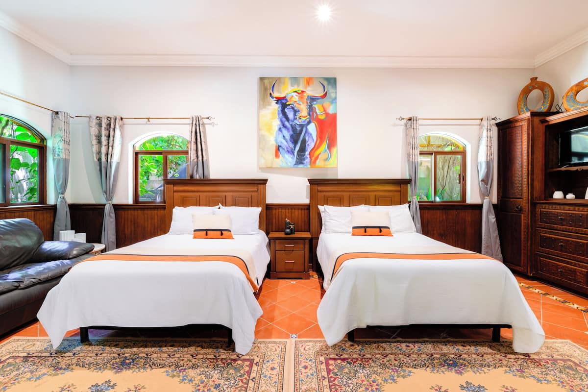 A hotel room with two beds, a wooden headboard, a large painting, and a TV.