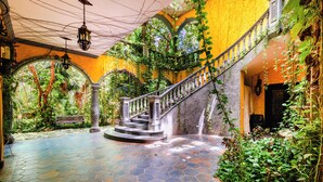 A staircase with a railing, surrounded by greenery and a tiled floor. - La Hacienda Hotel, at Xcaret (Playa del Carmen)