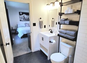 A modern bathroom with a white sink, black faucet, and a toilet. There is a towel rack with folded towels and a mirror above the sink. - Newly remodeled home on 2 acres. Close to Mt Baker Ski Area,Bellingham & Canada! (Bellingham)