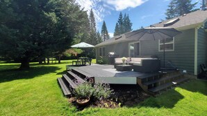 Une terrasse dotée de mobilier d’extérieur, d’un barbecue et d’un espace abrité avec un parasol.