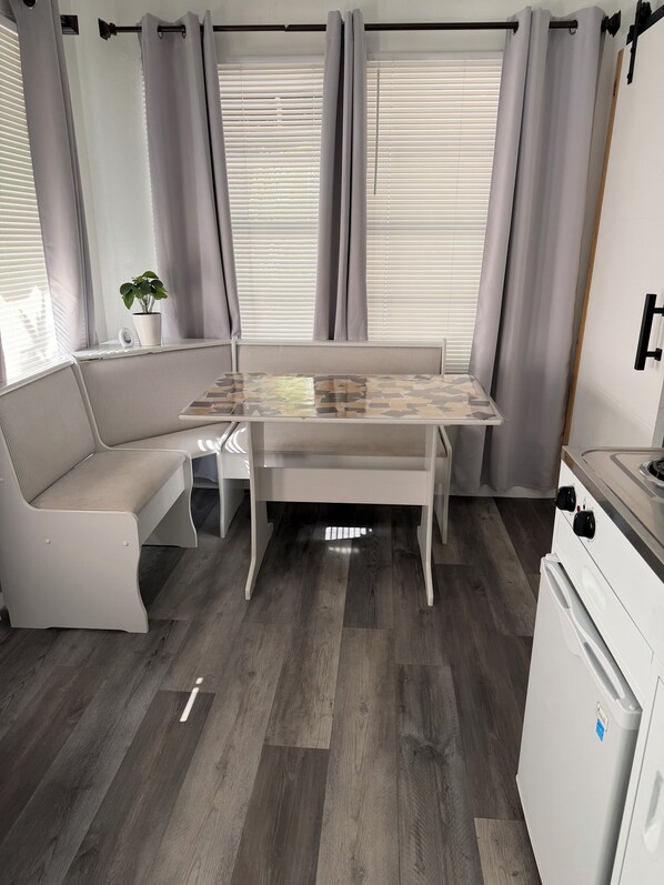 A compact living space with a built-in bench, a small table, and a kitchenette.