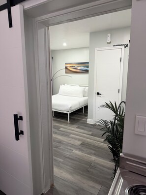 A hotel room with a bed, a painting, a plant, and a door labeled 'THINKING ROOM'.