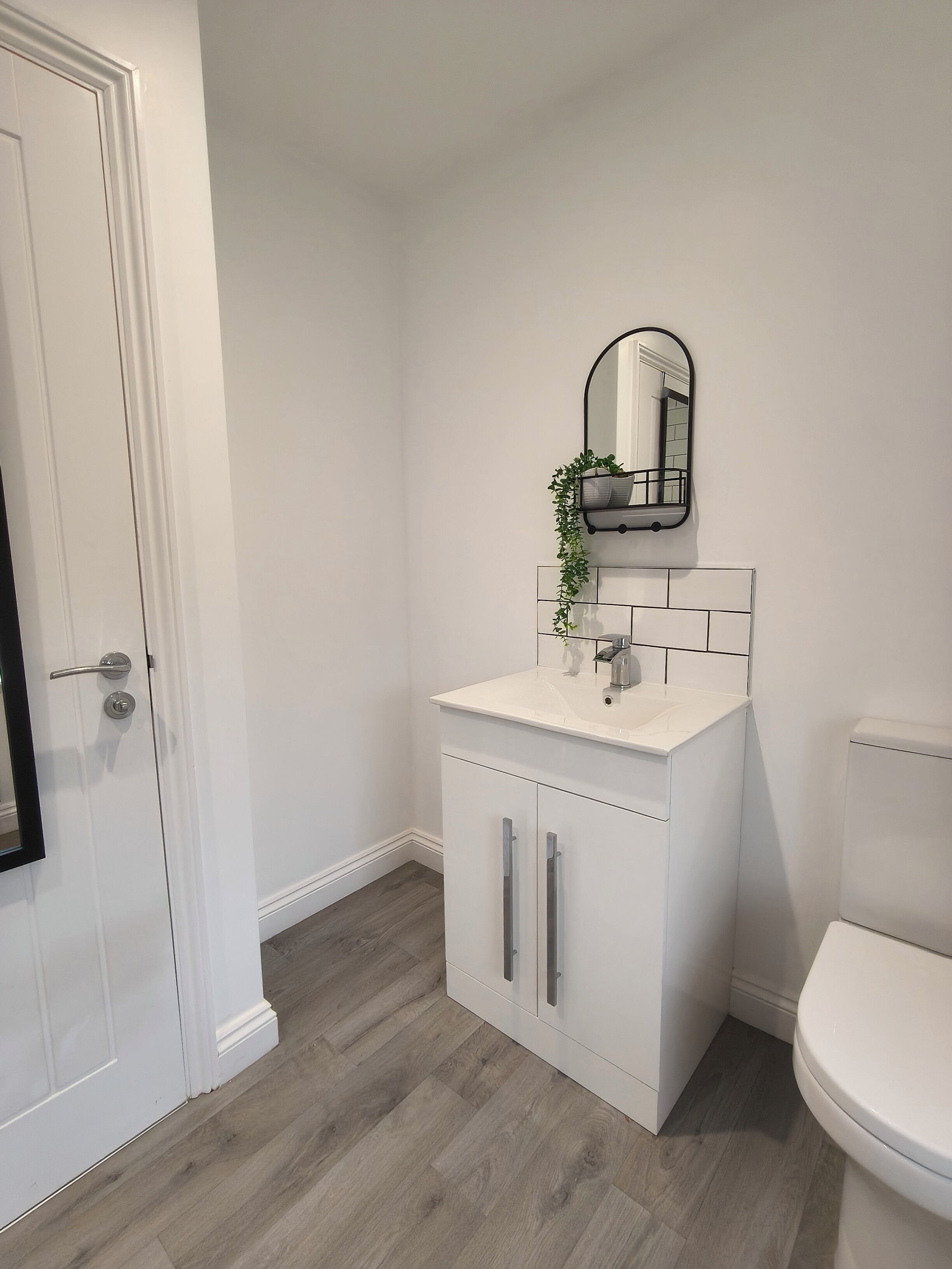 Une salle de bain avec un lavabo blanc, un miroir et des toilettes.