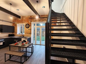 Una cocina moderna con comedor, una escalera y vista al patio trasero.