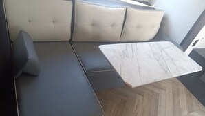 Una sala de estar moderna con un sofá gris oscuro, un banco con cojines color gris claro y una mesa de centro de mármol.