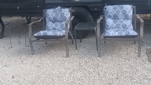 Una tienda de campaña con dos sillas, una mesa pequeña y una parrilla, decorada con un estampado geométrico.