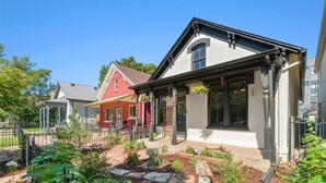 A residential house with a front porch, a garden with various plants, and a neighboring red house. - Charming and walkable downtown Denver RINO 3 bed home (Denver)