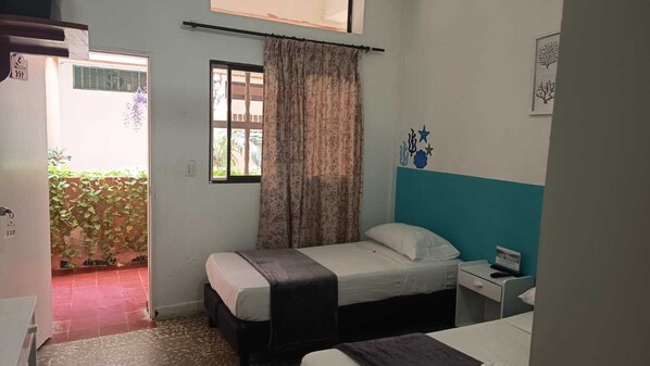 A small, single-bed room with a window, a bedside table, and a door leading to a balcony. - Hotel Monte Carlo (Tolú)