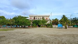 A building with multiple floors, a balcony, and a sandy foreground. - Hotel Monte Carlo (Tolú)