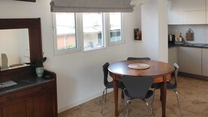 Un coin repas comprenant une table ronde, des chaises, un meuble en bois et un téléviseur fixé au mur.