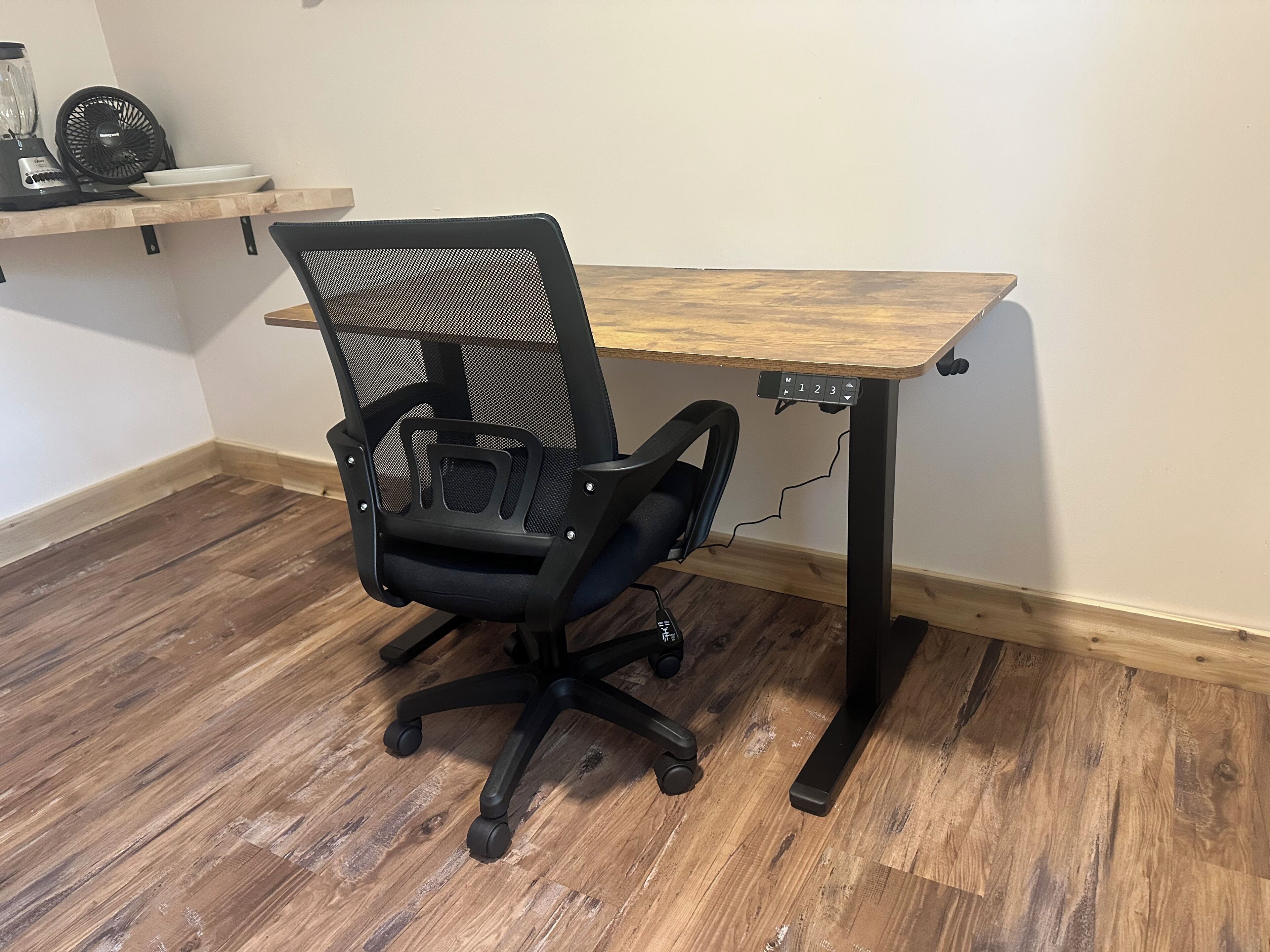 A wooden desk with a black mesh office chair.