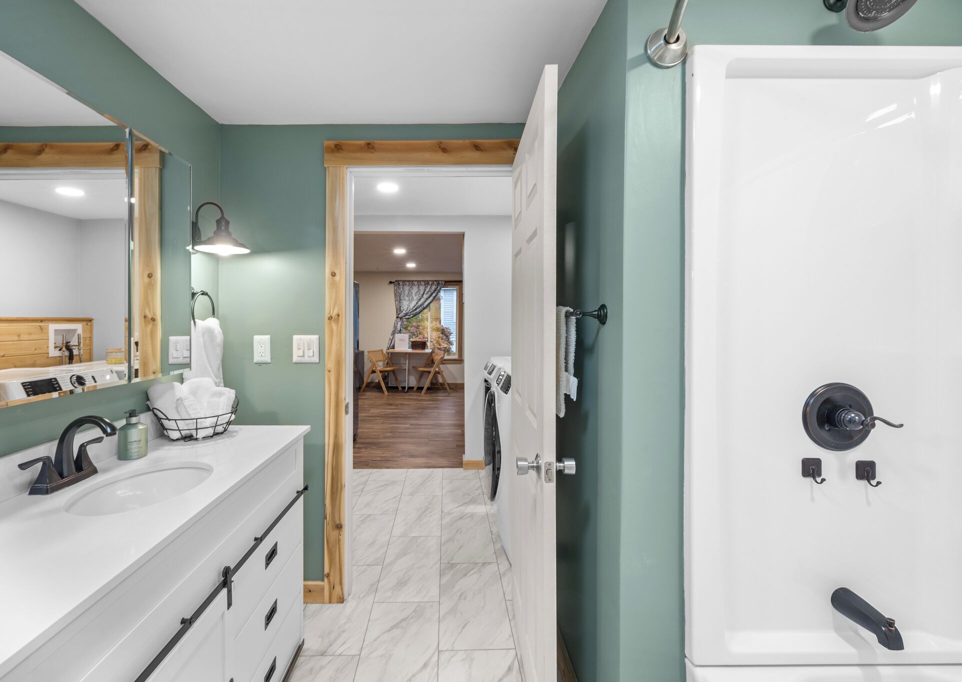 A modern bathroom with a large mirror, white sink, and a walk-in shower.
