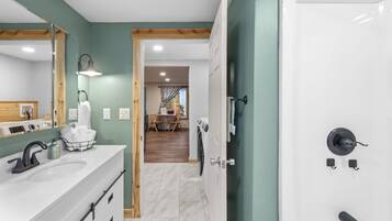 A modern bathroom with a large mirror, white sink, and a walk-in shower.