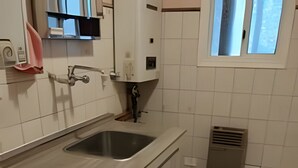 Ett kök med en dubbeldiskho, träskåp och ett fönster.