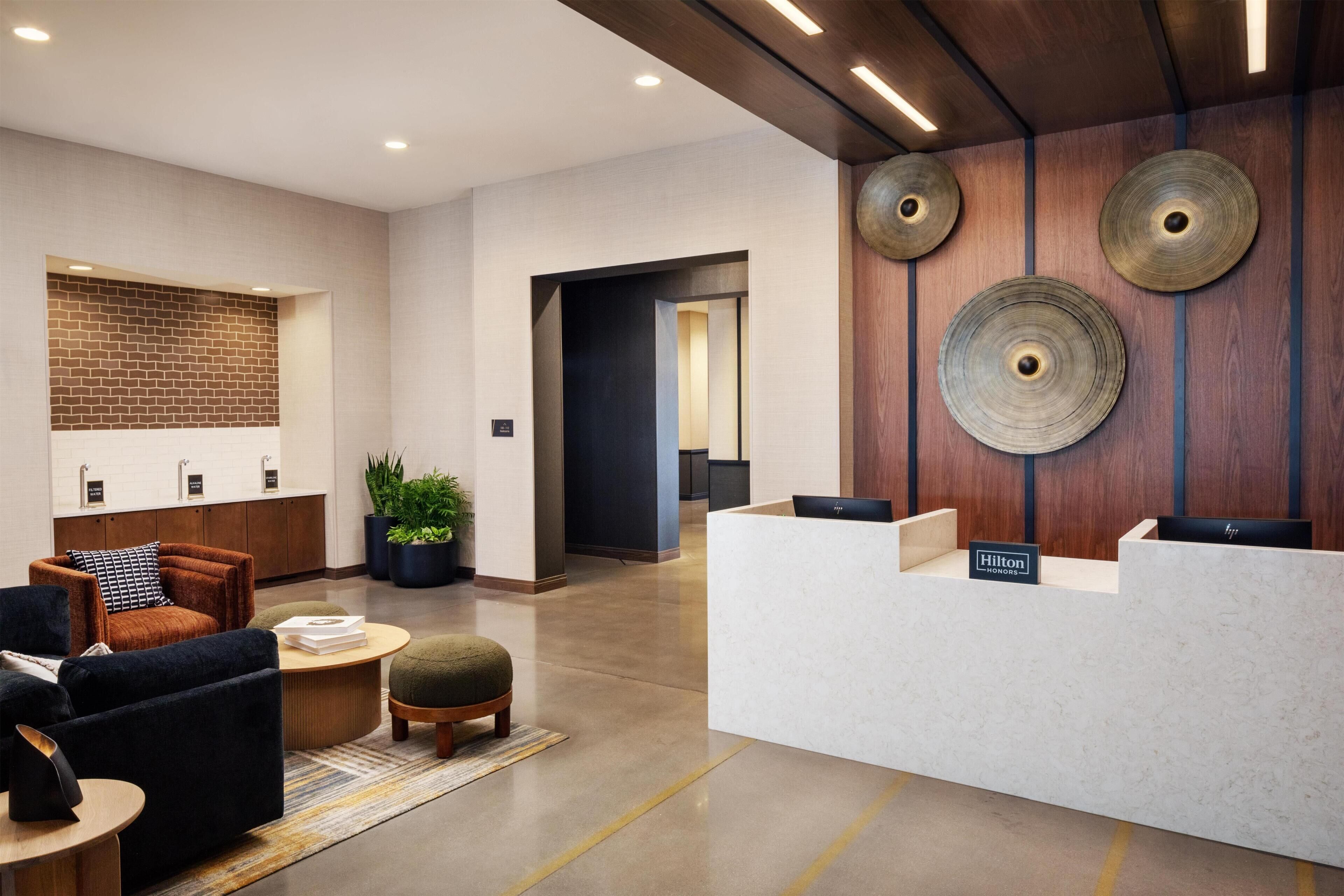 Una hall d'hotel moderna con reception, area salotto e parete decorata con mattoni.