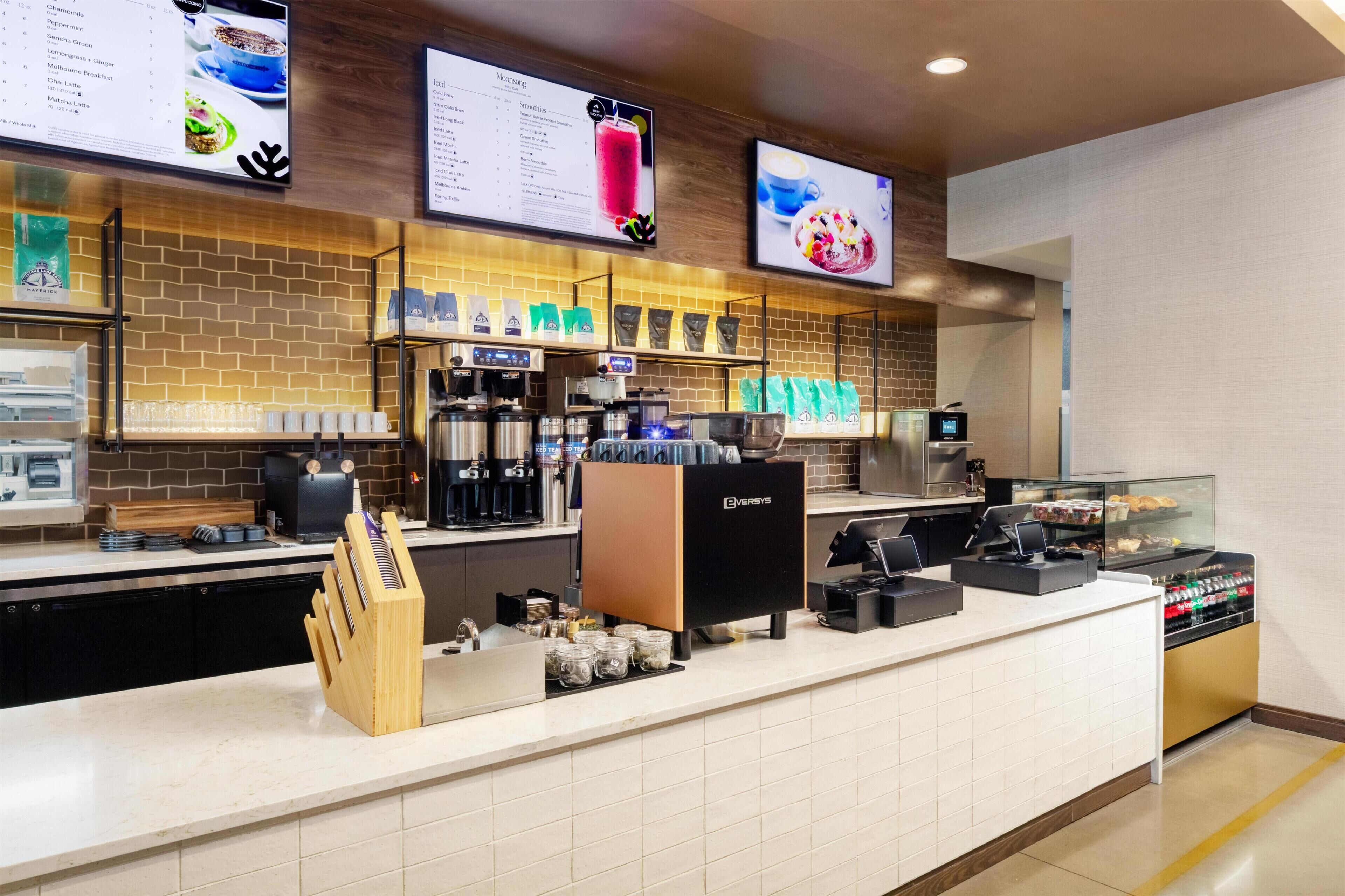 L’intérieur d’un café moderne, avec un comptoir, des machines à café et des panneaux affichant le menu.