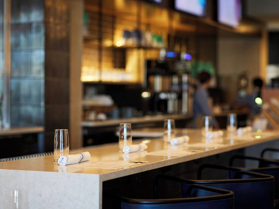A bar area with a long counter, glasses, and towels.