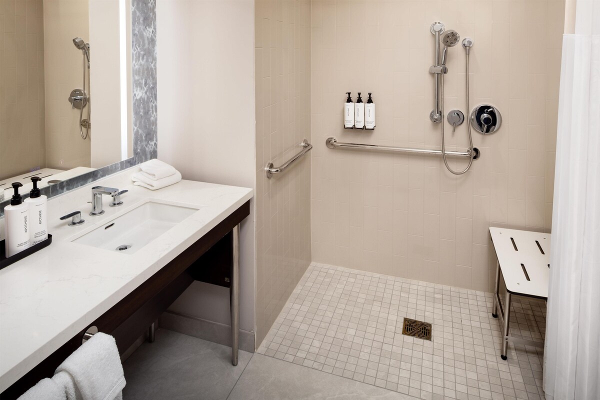 A modern bathroom with a shower, a vanity with a sink, and a towel rack.