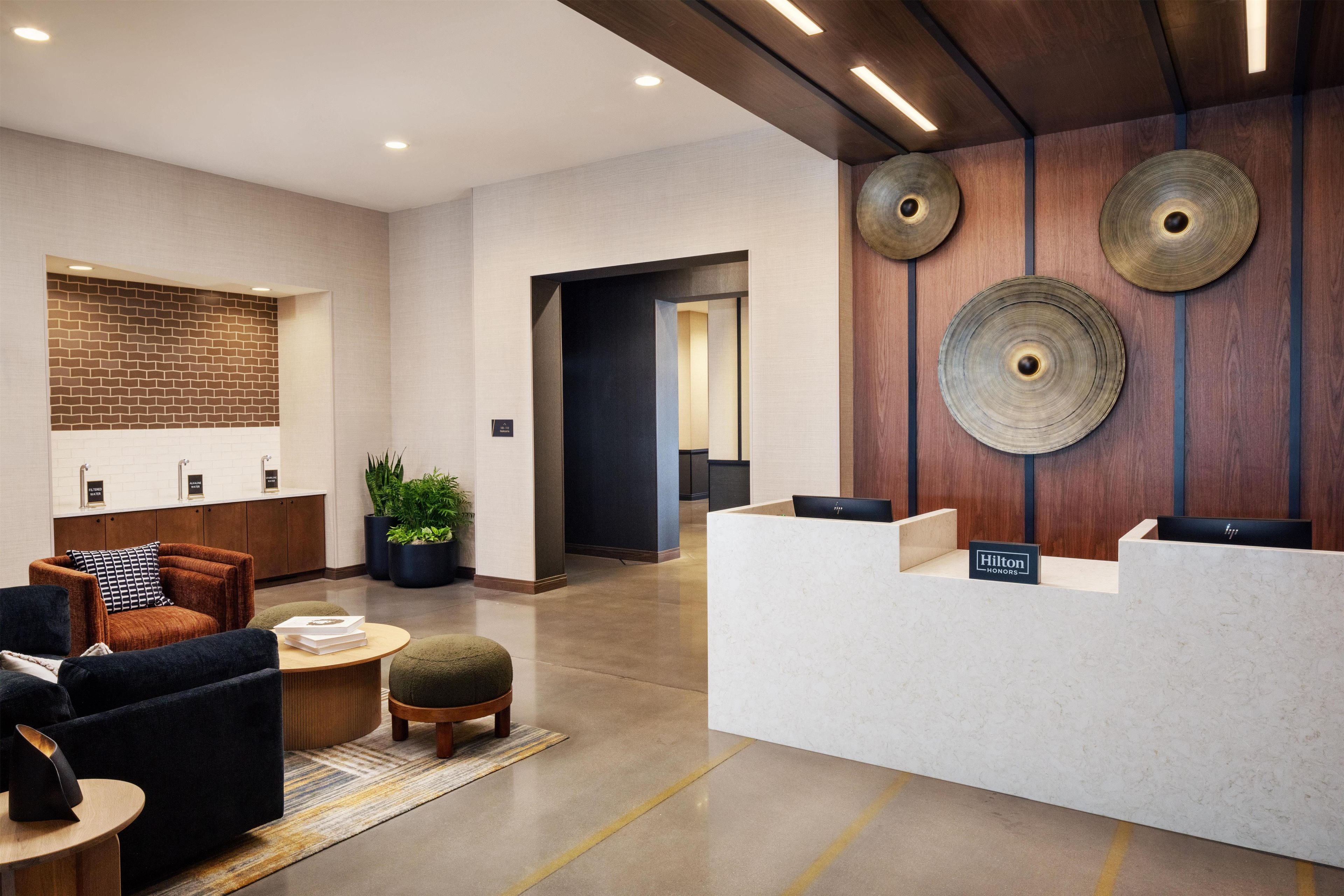 A hotel lobby with a reception desk, seating area, and a brick-patterned wall.