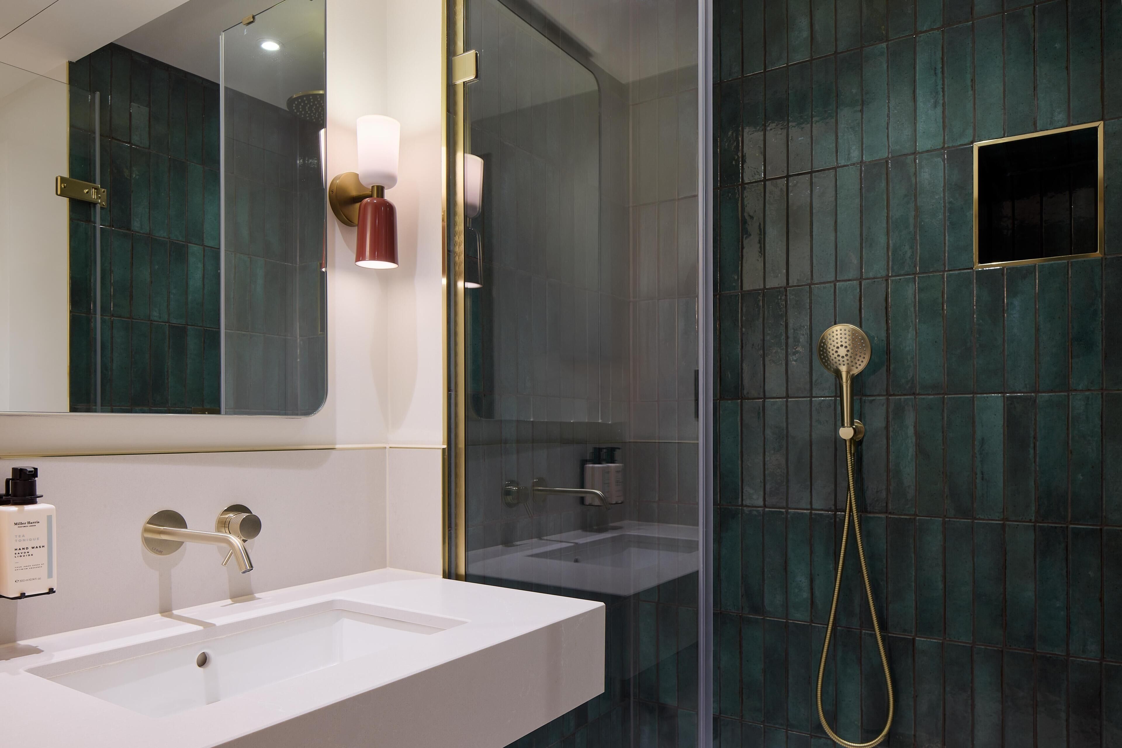 A modern bathroom with a white sink, a glass-enclosed shower, and a large mirror with wall-mounted lights.