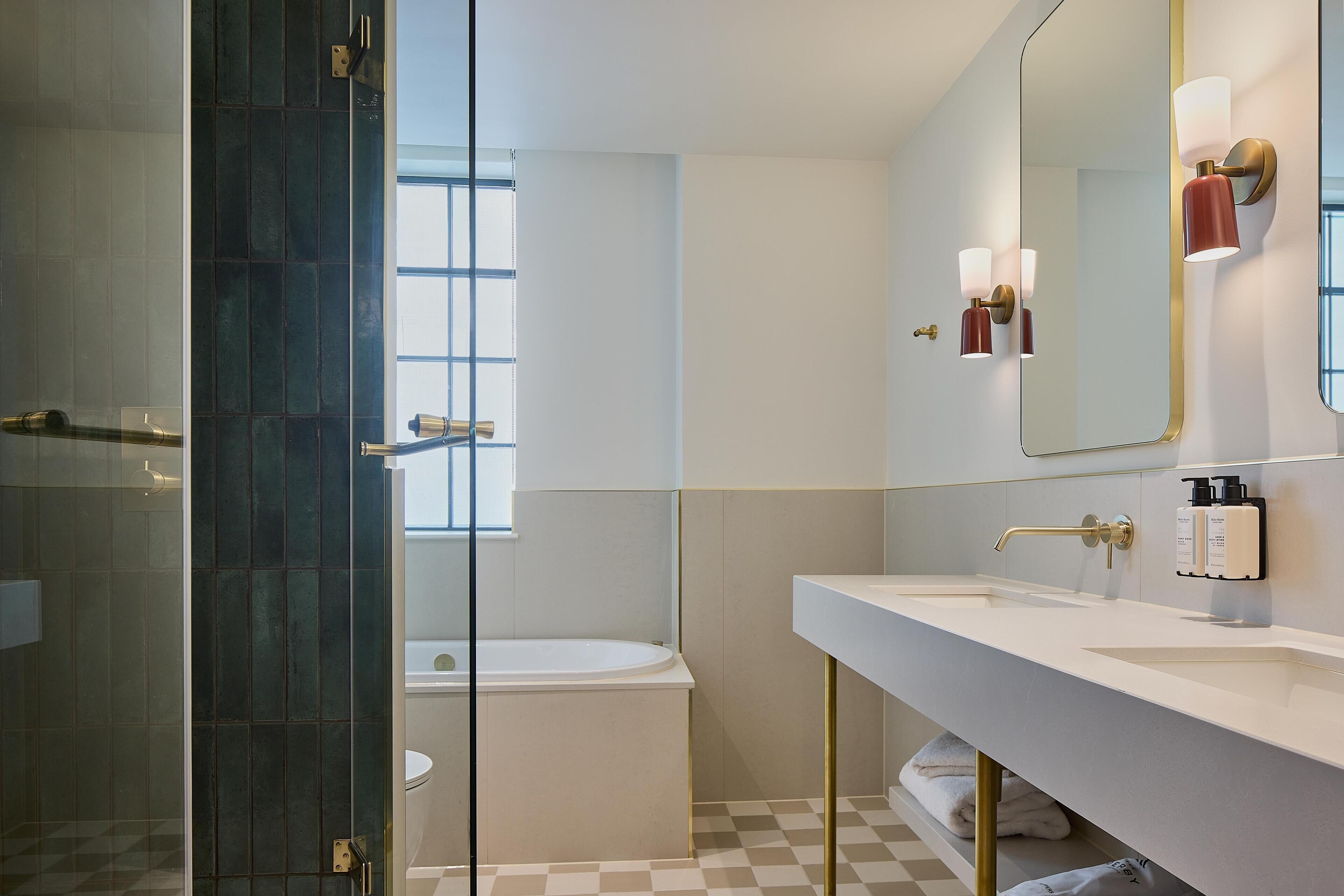 A modern bathroom with a glass shower enclosure, a bathtub, and a large mirror with wall-mounted lights.