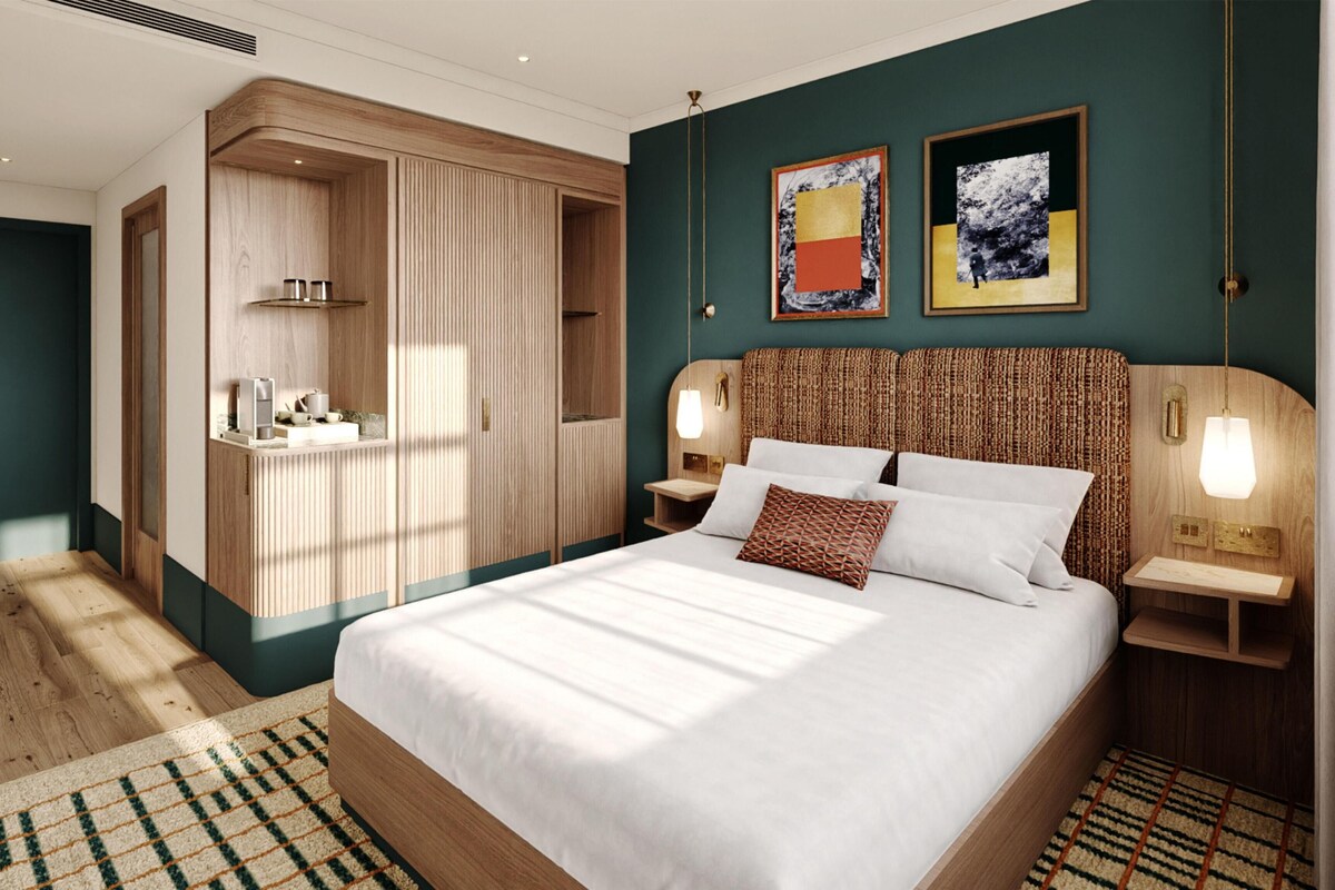 A bedroom with a large bed, bedside tables, a wardrobe, and artwork on the wall.